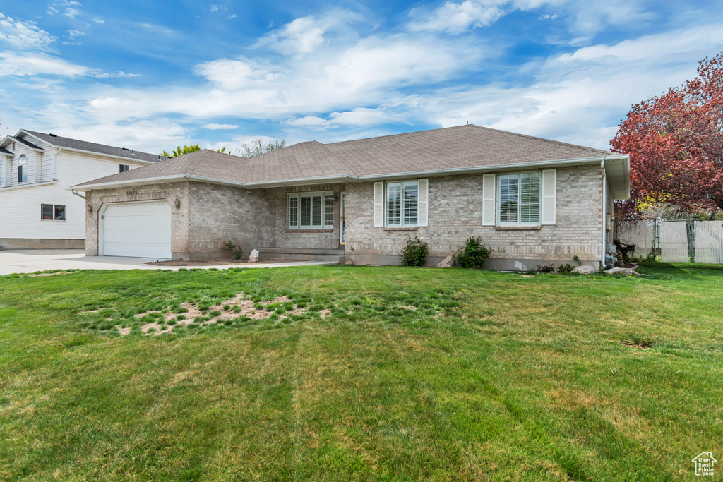 View of front of house featuring a garage, brick siding, fence, a front lawn, and concrete driveway