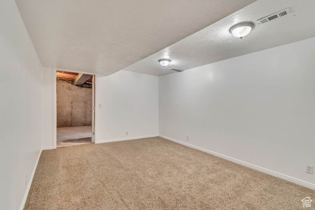 Finished below grade area featuring visible vents, carpet flooring, and baseboards