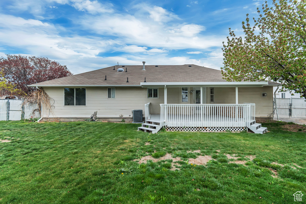 Back of house featuring a lawn, fence, and cooling unit