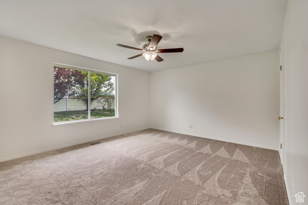 Carpeted spare room featuring baseboards, ceiling fan, and visible vents
