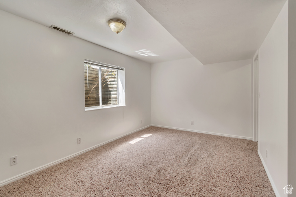 Carpeted spare room with visible vents and baseboards