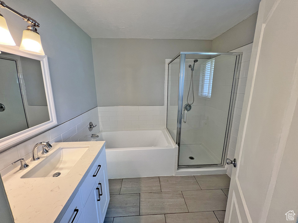 Full bath with a shower stall, vanity, a garden tub, and tile patterned flooring