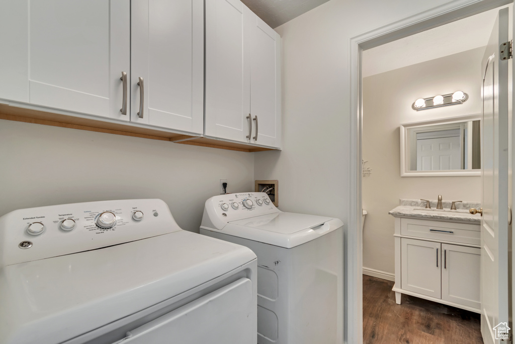 Washroom with separate washer and dryer, baseboards, dark wood-style floors, and a sink