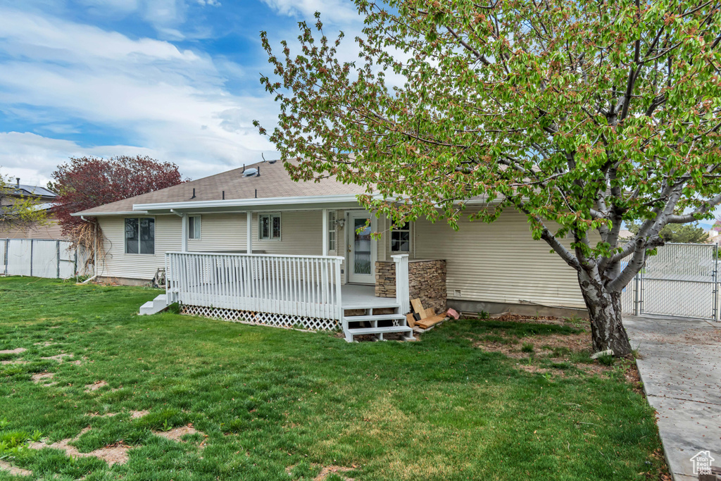Rear view of house with a lawn, fence, and a deck