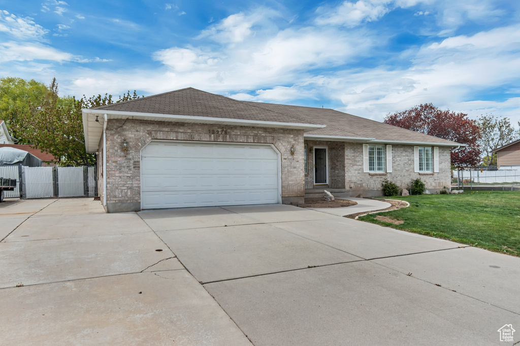 Ranch-style home featuring fence, a garage, driveway, and a front yard
