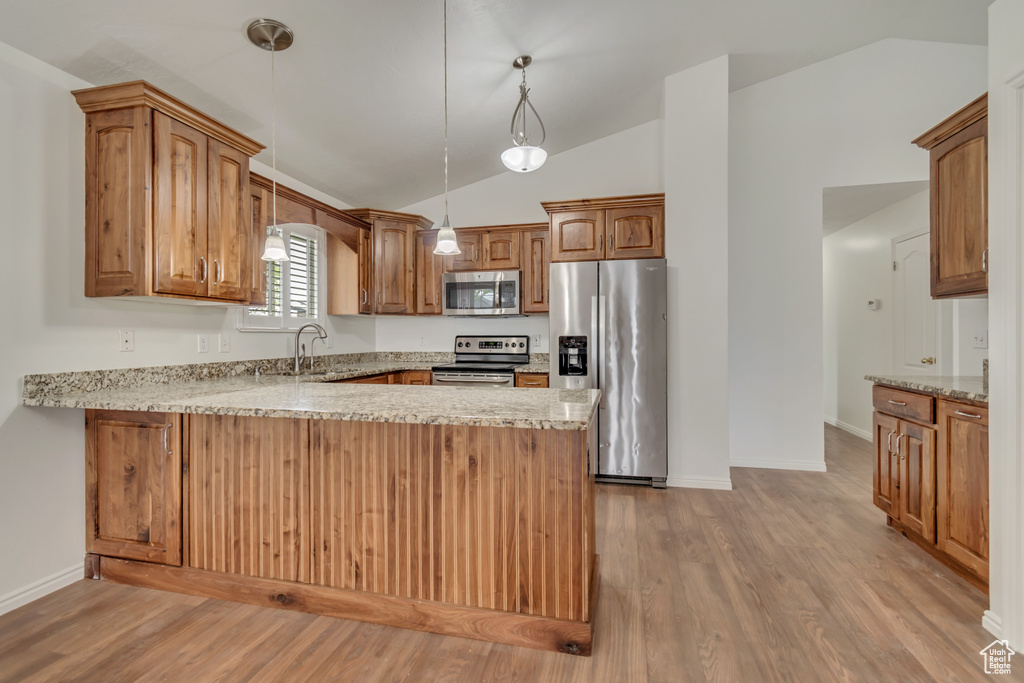 Kitchen with light wood-type flooring, a peninsula, a sink, and appliances with stainless steel finishes