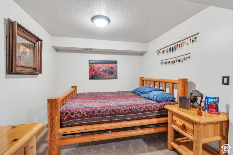 Bedroom with a textured ceiling and carpet