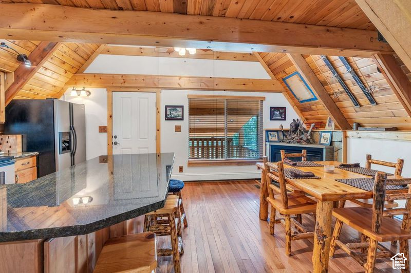 Dining area featuring wood ceiling, lofted ceiling with beams, and light wood-type flooring