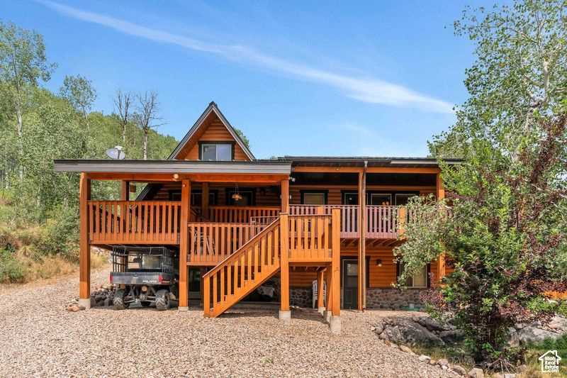 Rear view of house featuring stairs and log veneer siding