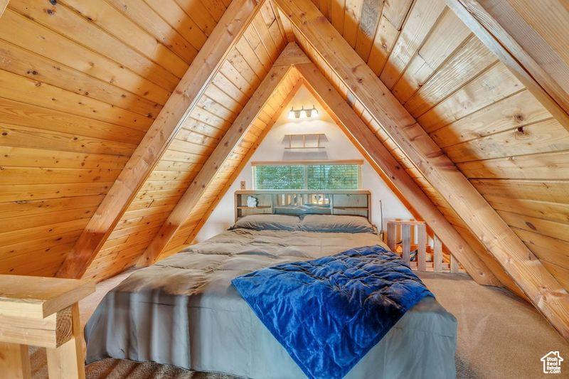 Bedroom with carpet floors, wood ceiling, and lofted ceiling