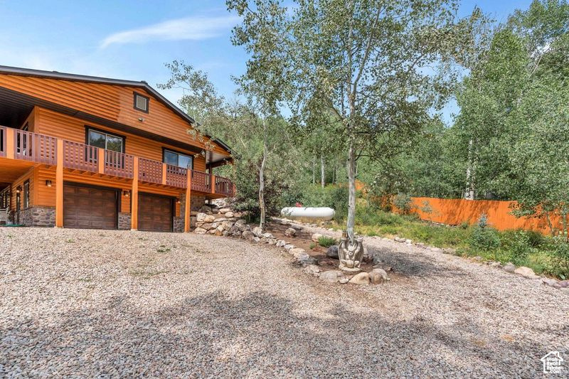 View of yard featuring fence, an attached garage, and gravel driveway