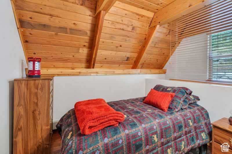Bedroom with lofted ceiling with beams, wood finished floors, and wooden ceiling