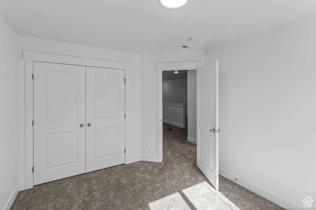 Unfurnished bedroom with carpet floors, baseboards, a closet, and visible vents