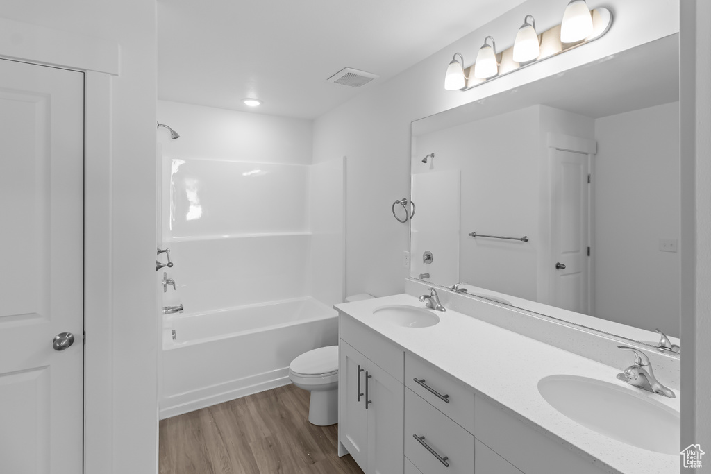 Full bath featuring double vanity, a sink, shower / bathing tub combination, and wood finished floors