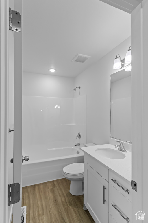 Bathroom with vanity, visible vents, wood finished floors, toilet, and  shower combination