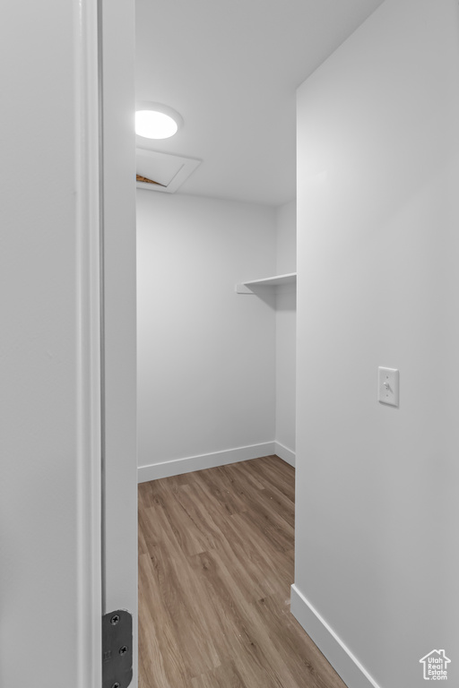 Walk in closet featuring wood finished floors and attic access