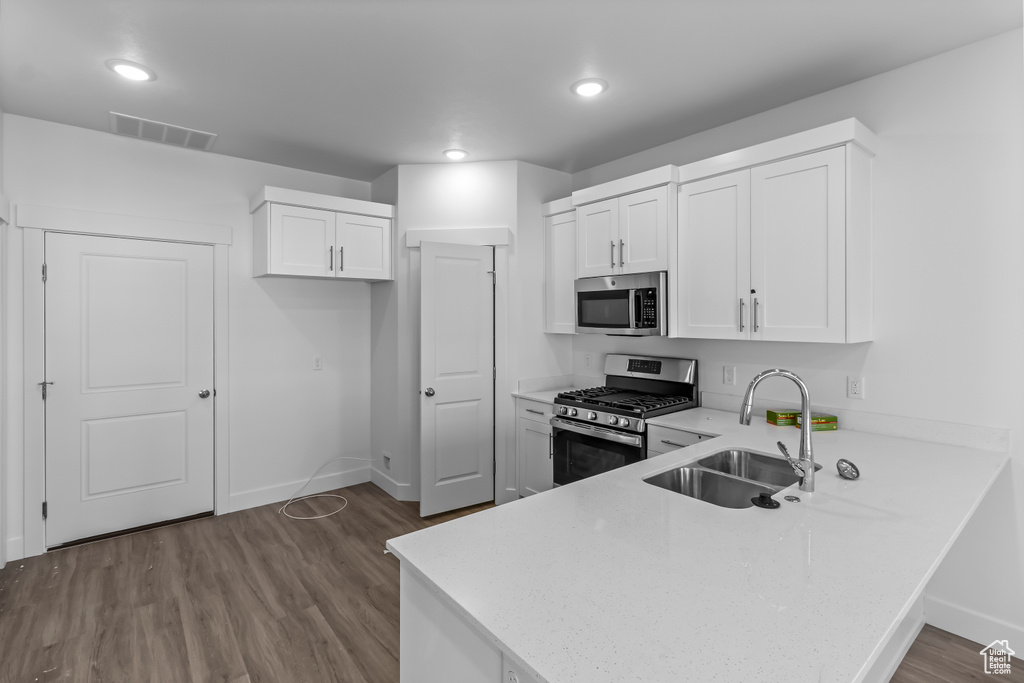 Kitchen with a peninsula, baseboards, light countertops, a sink, and stainless steel appliances