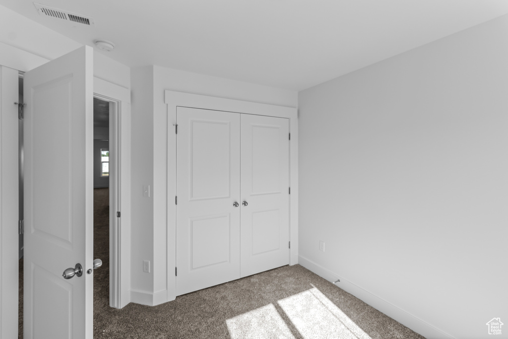 Unfurnished bedroom featuring carpet flooring, baseboards, visible vents, and a closet