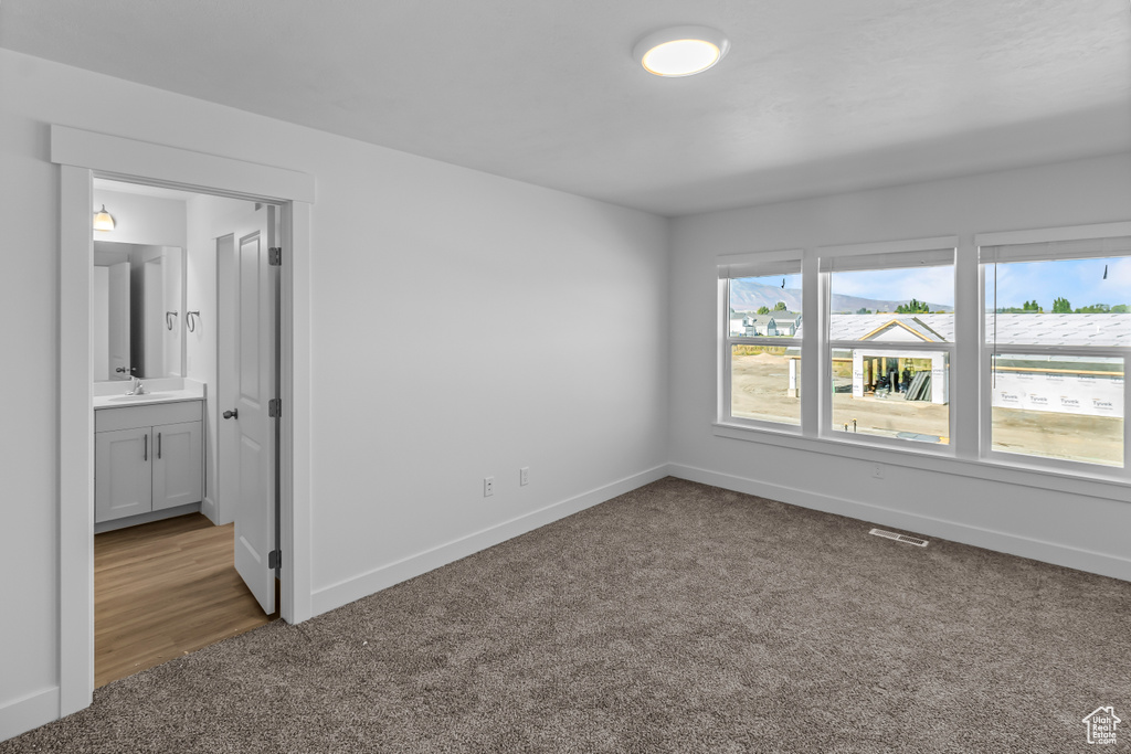 Unfurnished bedroom featuring carpet floors, a sink, baseboards, and visible vents