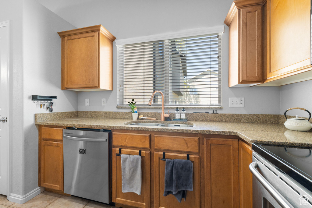 Kitchen with a sink, brown cabinets, light tile patterned floors, dishwasher, and light countertops