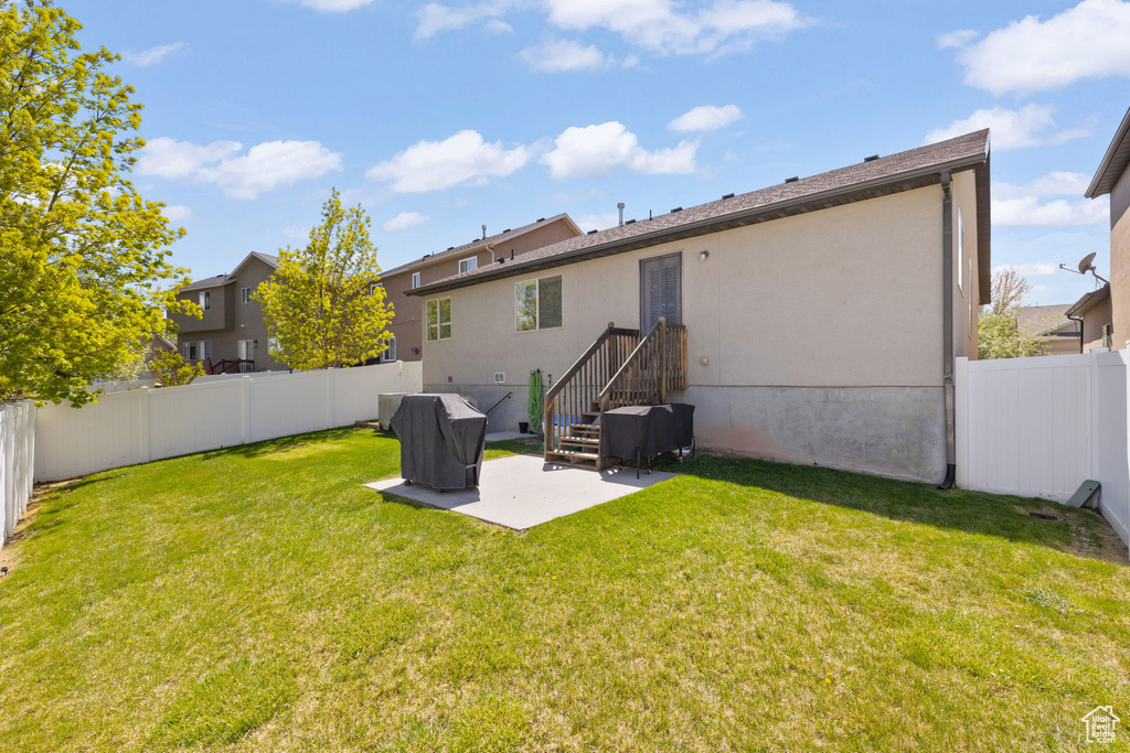 Back of property featuring a yard, a patio area, a fenced backyard, and stucco siding