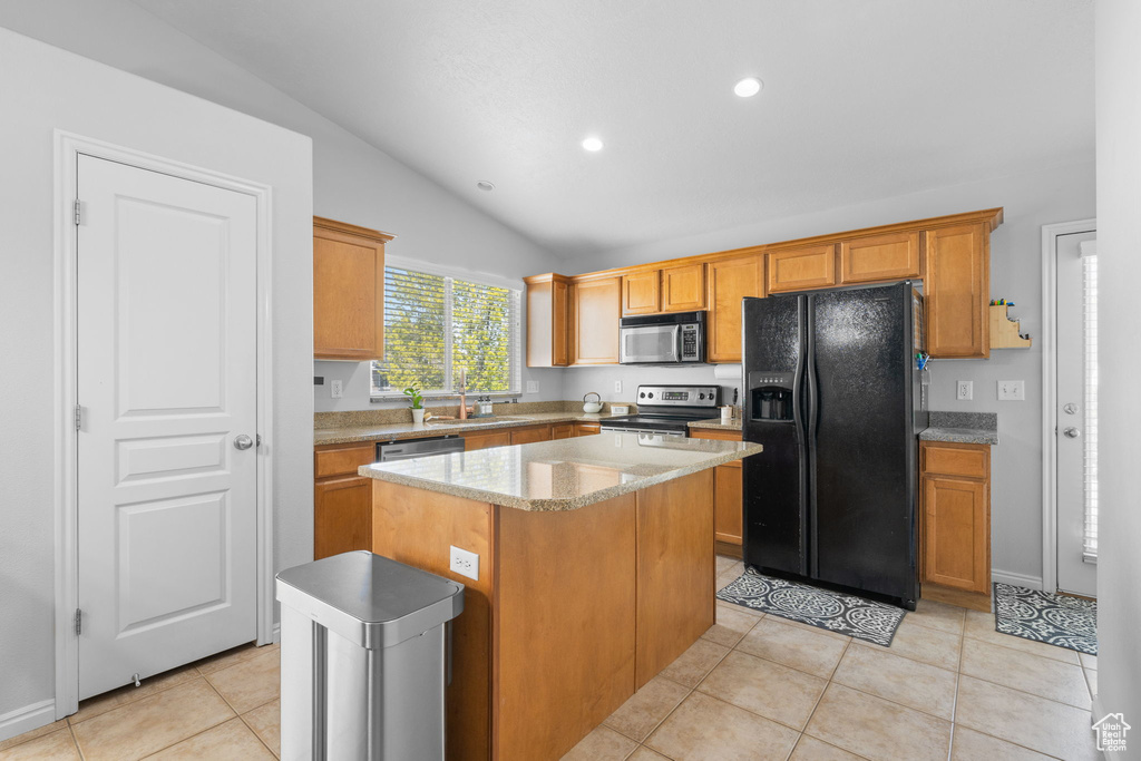 Kitchen featuring a center island, recessed lighting, lofted ceiling, appliances with stainless steel finishes, and light tile patterned floors
