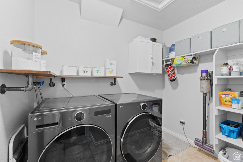Laundry room with washing machine and dryer, baseboards, and cabinet space