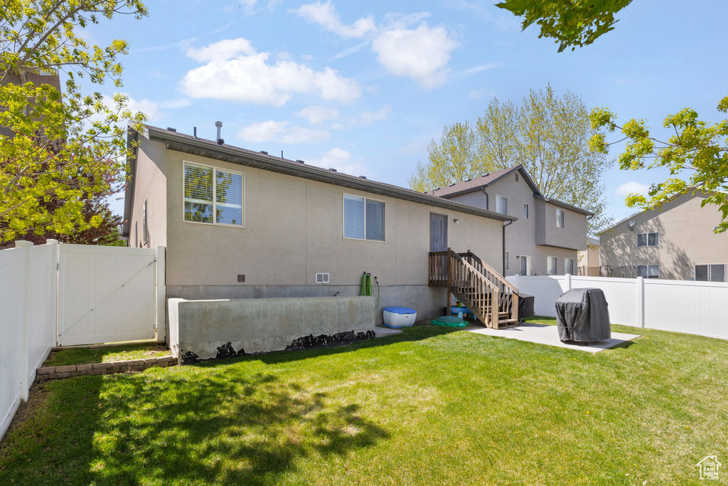 Back of property with a lawn, a fenced backyard, a gate, and a patio