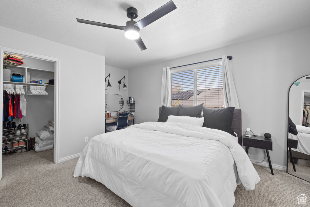 Carpeted bedroom featuring a ceiling fan, baseboards, and a closet