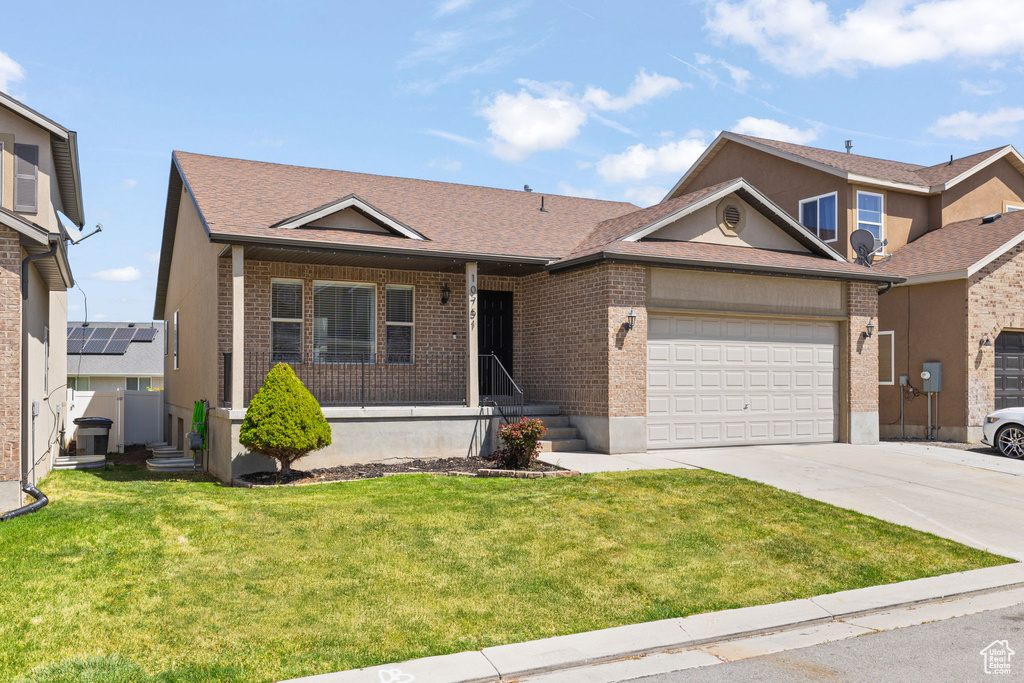 Ranch-style house featuring a front lawn, driveway, a porch, a garage, and brick siding