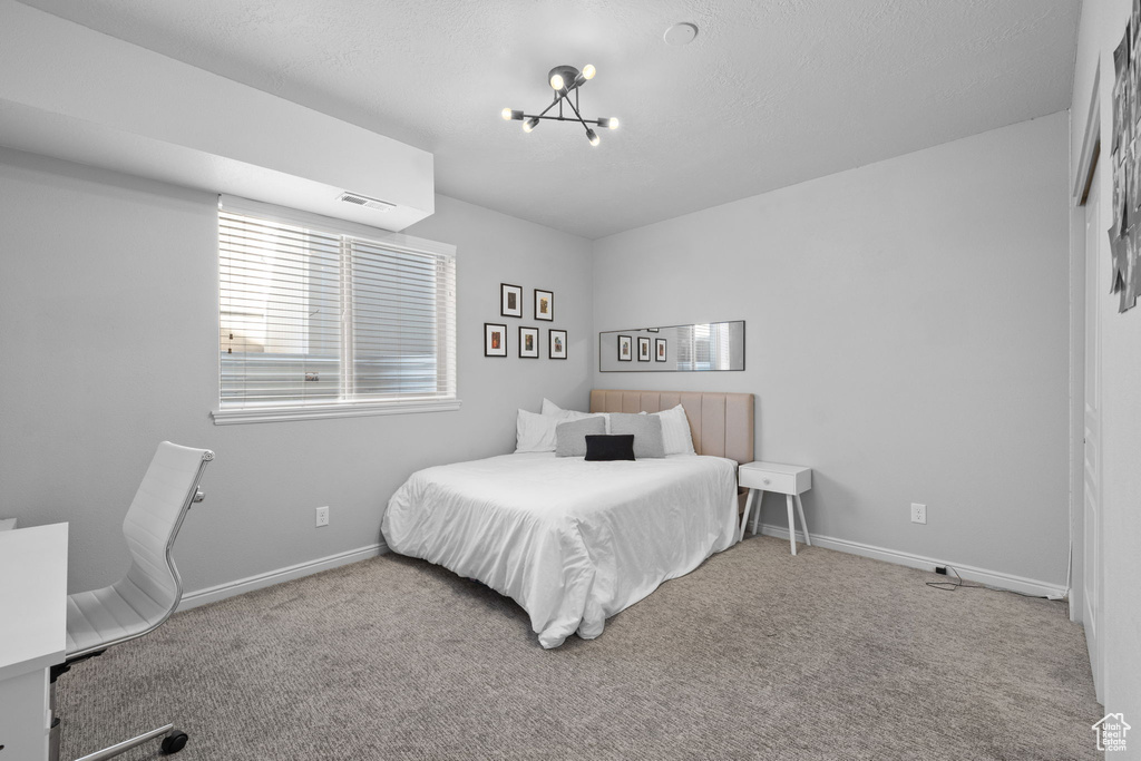 Carpeted bedroom featuring visible vents, baseboards, and an inviting chandelier