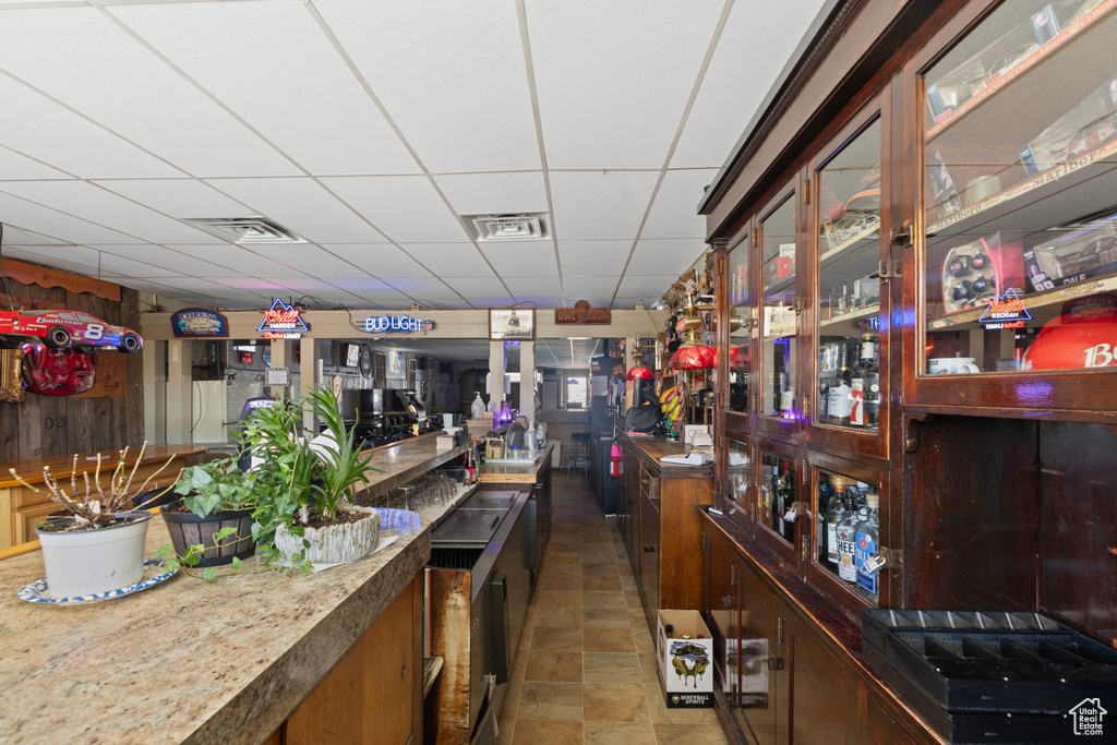 Bar with visible vents, a drop ceiling, and stone finish floor
