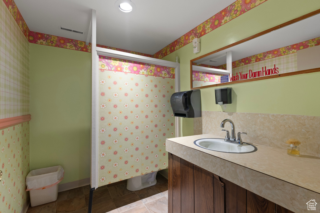 Full bathroom featuring vanity, decorative backsplash, walk in shower, and visible vents