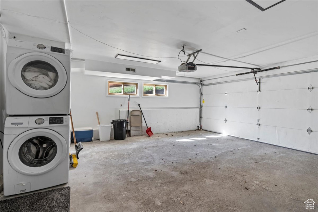 Garage featuring stacked washing maching and dryer, a garage door opener, and visible vents