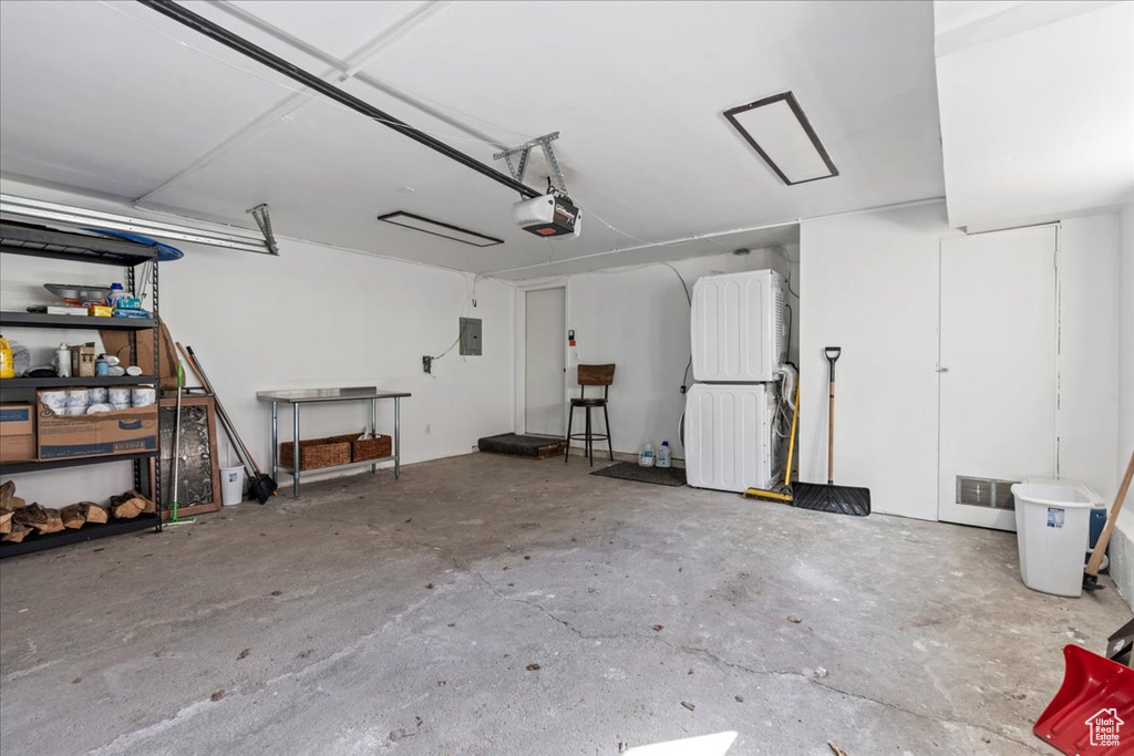 Garage featuring electric panel, a garage door opener, and visible vents
