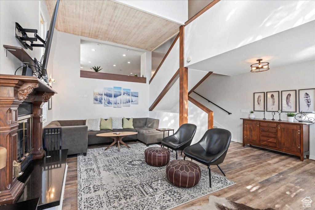 Living area featuring a fireplace with raised hearth, stairs, wood finished floors, and wood ceiling