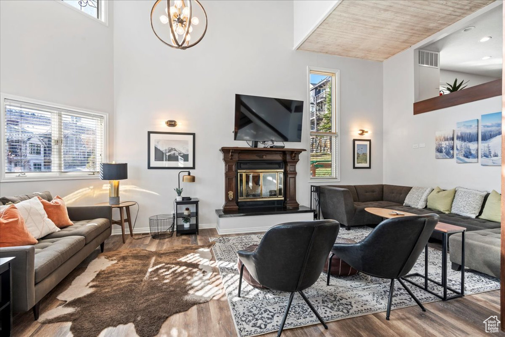 Living area with visible vents, a towering ceiling, wood finished floors, and a chandelier