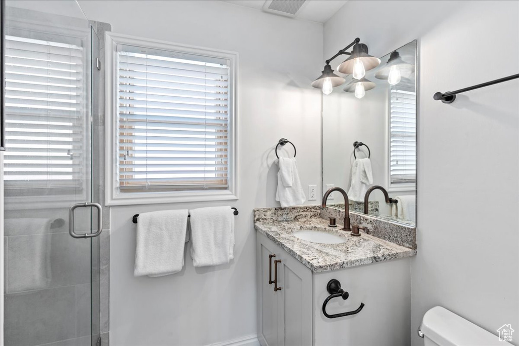 Full bath featuring vanity, toilet, visible vents, and a stall shower