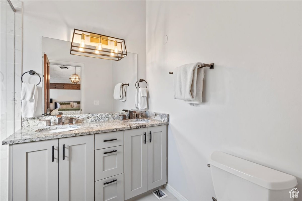 Ensuite bathroom with connected bathroom, a sink, toilet, double vanity, and visible vents