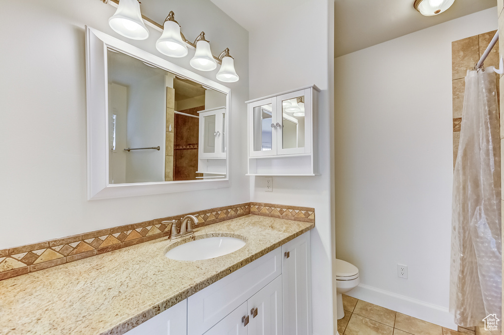 Bathroom with curtained shower, vanity, toilet, and tile patterned flooring