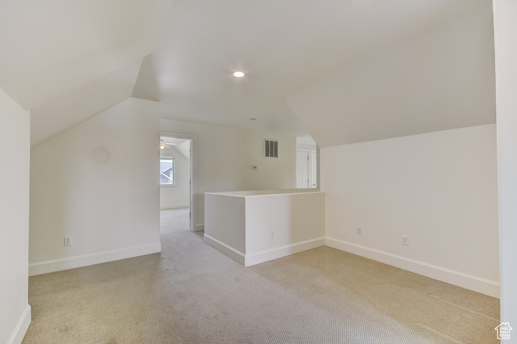 Additional living space with lofted ceiling, visible vents, baseboards, recessed lighting, and light carpet