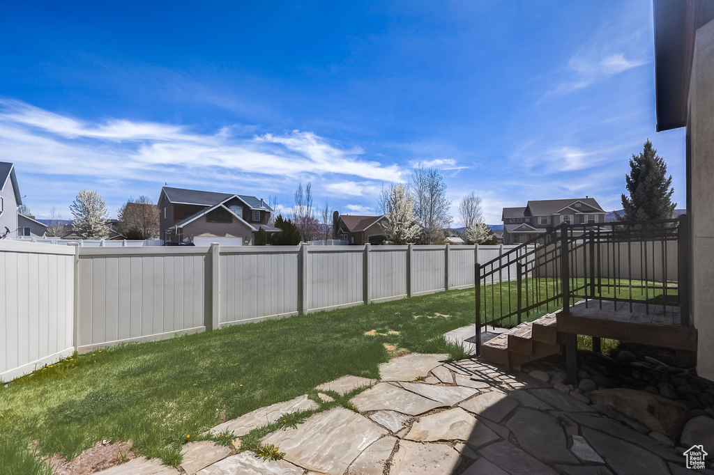 View of yard featuring a patio, a fenced backyard, and a residential view