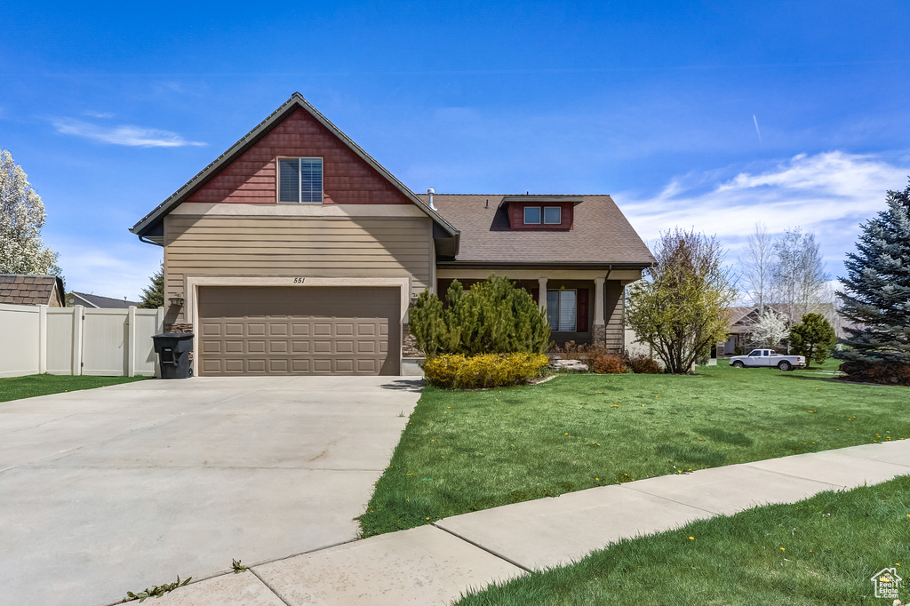 Craftsman-style house with driveway, fence, a front lawn, and a garage
