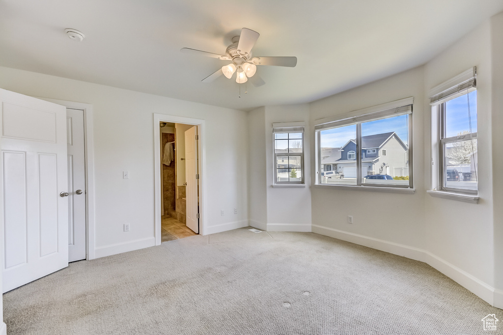 Unfurnished bedroom with multiple windows, light carpet, and baseboards