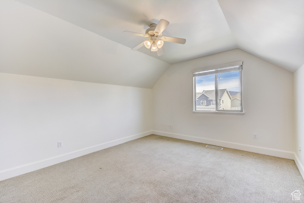 Additional living space featuring ceiling fan, visible vents, vaulted ceiling, light carpet, and baseboards