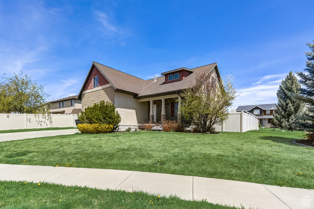Craftsman inspired home with fence, covered porch, a front yard, and a shingled roof