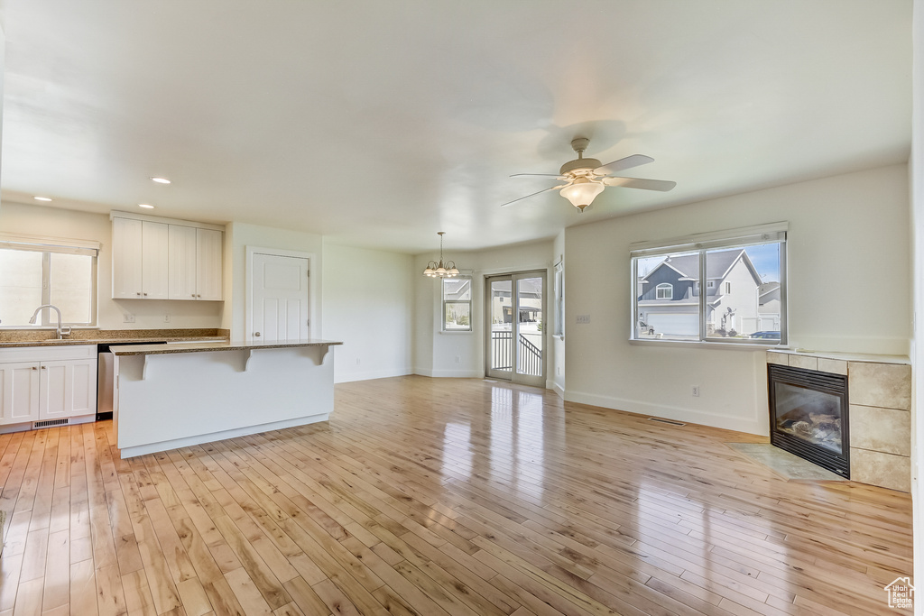 Interior space with a breakfast bar, white cabinets, light wood-style flooring, and a fireplace