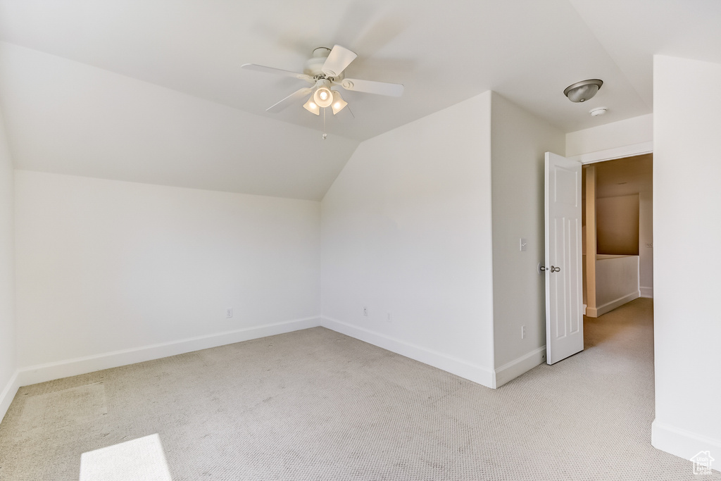 Bonus room with ceiling fan, vaulted ceiling, light carpet, and baseboards