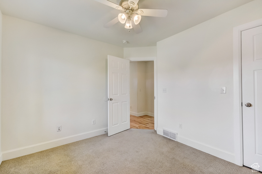 Unfurnished bedroom featuring light colored carpet, visible vents, ceiling fan, and baseboards