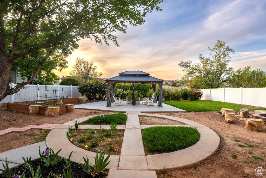 View of community featuring a gazebo, a fenced backyard, a patio area, and a garden
